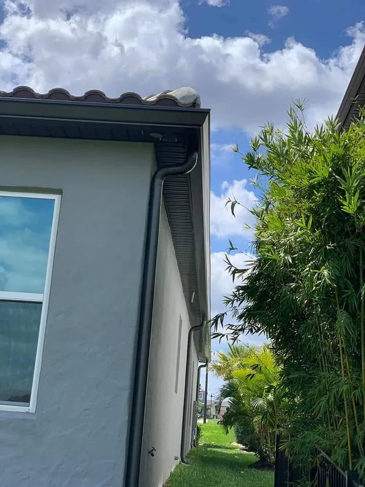 Low angle black round downspout gray stucco barrel tile eave, Sanford